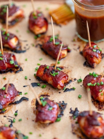 Close up of a chicken bacon BBQ bite slathered in BBQ sauce and garnished with chives.