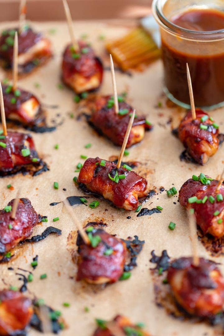 Close up of a chicken bacon BBQ bite slathered in BBQ sauce and garnished with chives.