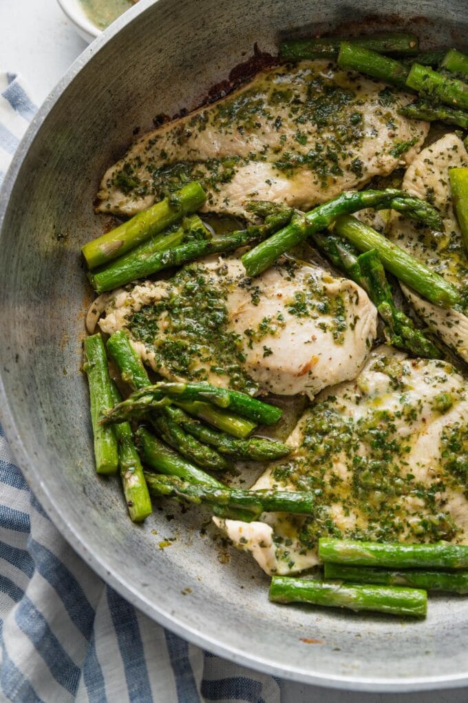 Chimichurri chicken breasts and asparagus spears cooked in a skillet and ready to serve with an extra sprinkle of sea salt.