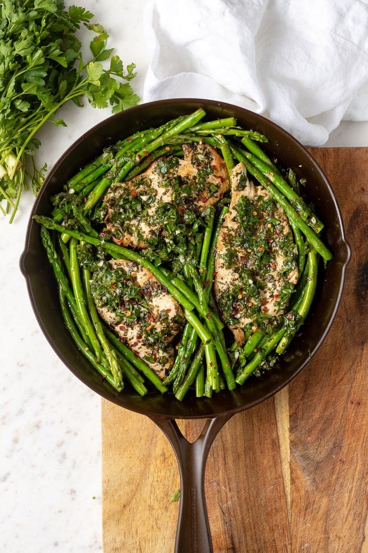A one-skillet dish of chimichurri chicken with asparagus, featured in a beautiful cast-iron skillet made in the USA by Marquette Castings.