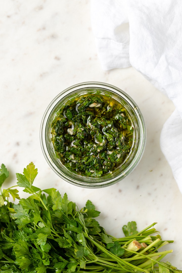 Close-up of a bowl of bright green chimichurri made by hand.
