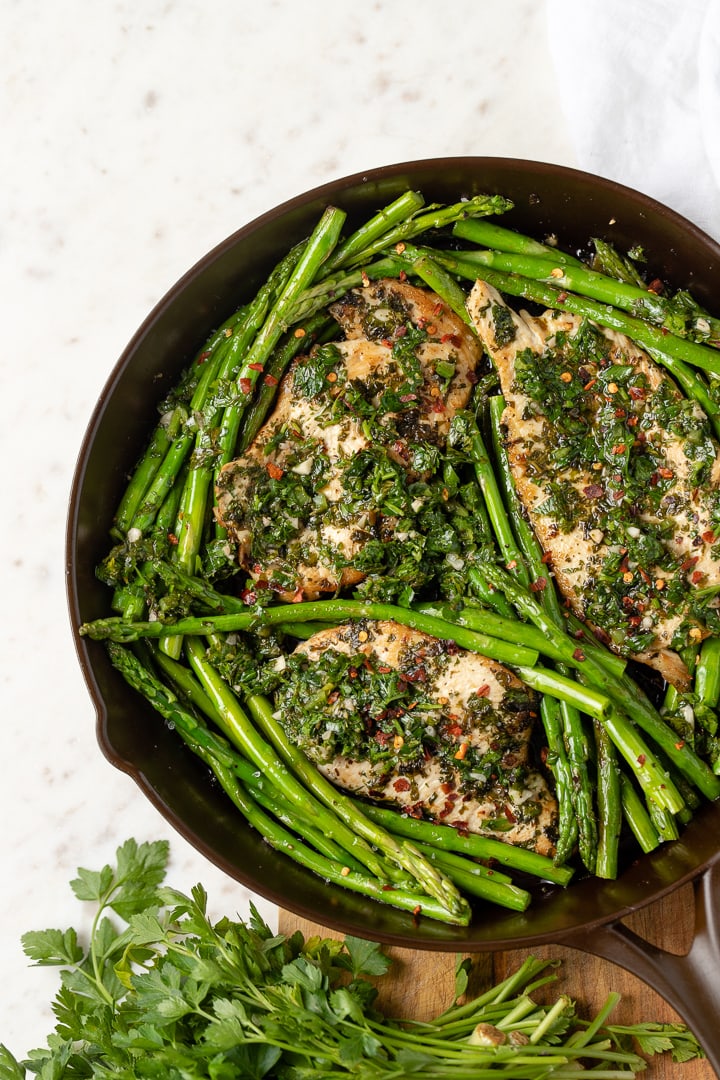 A one-skillet dish of chimichurri chicken with asparagus, featured in a beautiful cast-iron skillet made in the USA by Marquette Castings.