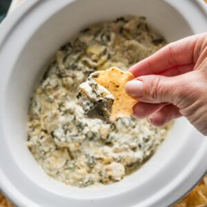 Close up of a tortilla scoop filled with spinach artichoke dip.
