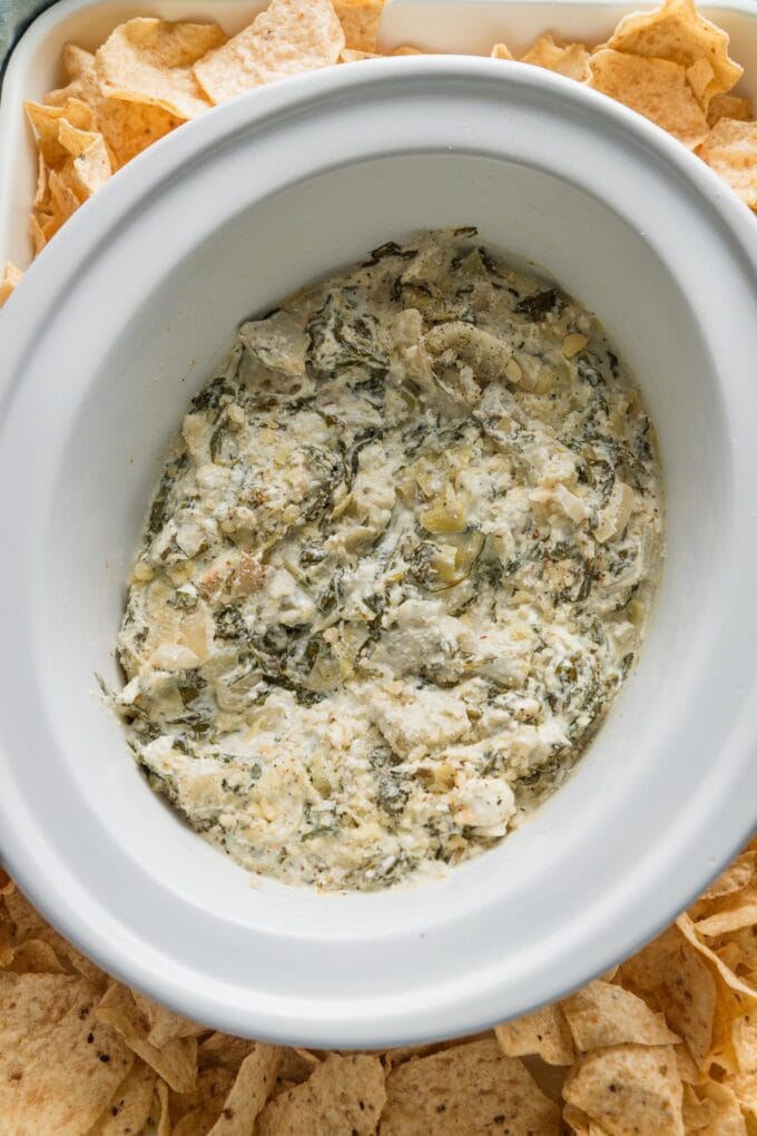 Skinny spinach artichoke dip made in a slow cooker and ready to serve with tortilla chips.