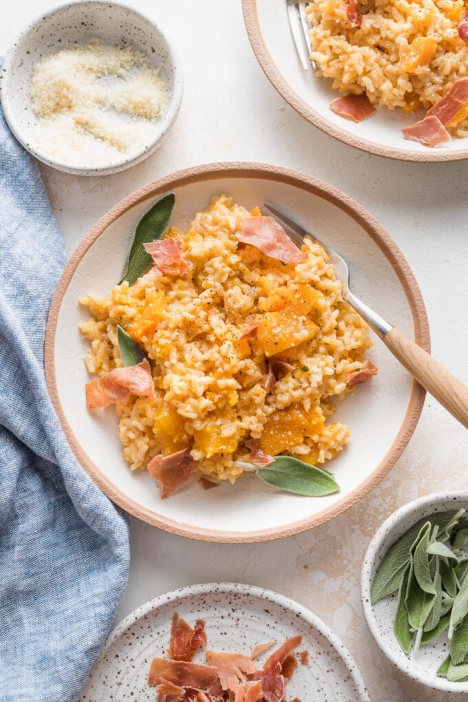 Fork posed in a bowl of risotto with butternut squash.