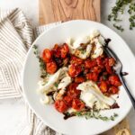 A white plate with a roasted tomato winter Caprese salad on it.