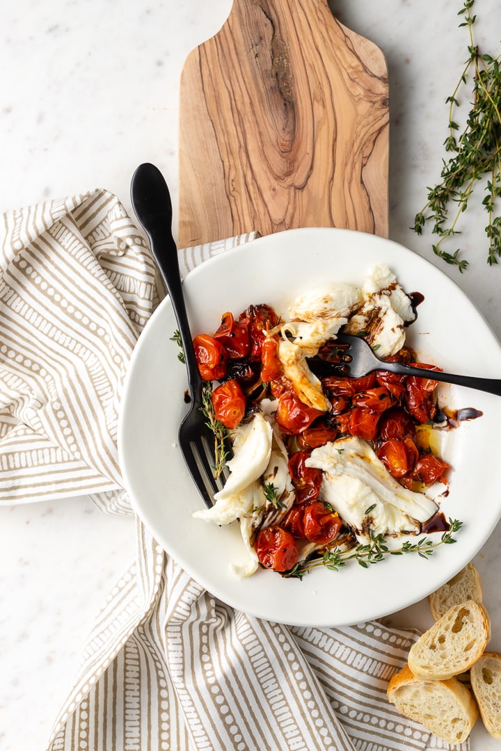 A winter Caprese salad with roasted tomatoes plated with two forks, for sharing!