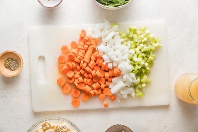 Carrots, onion, and celery chopped on a cutting board.