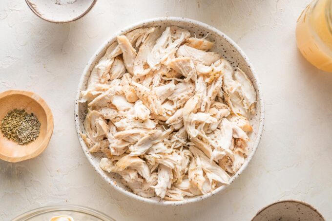 Shredded chicken in a bowl, ready to mix back into soup.