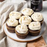 A small plate filled with the best chocolate Guinness cupcakes with Irish cream frosting, with a bottle of Guinness in the background.