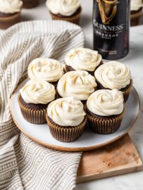 A small plate filled with the best chocolate Guinness cupcakes with Irish cream frosting, with a bottle of Guinness in the background.