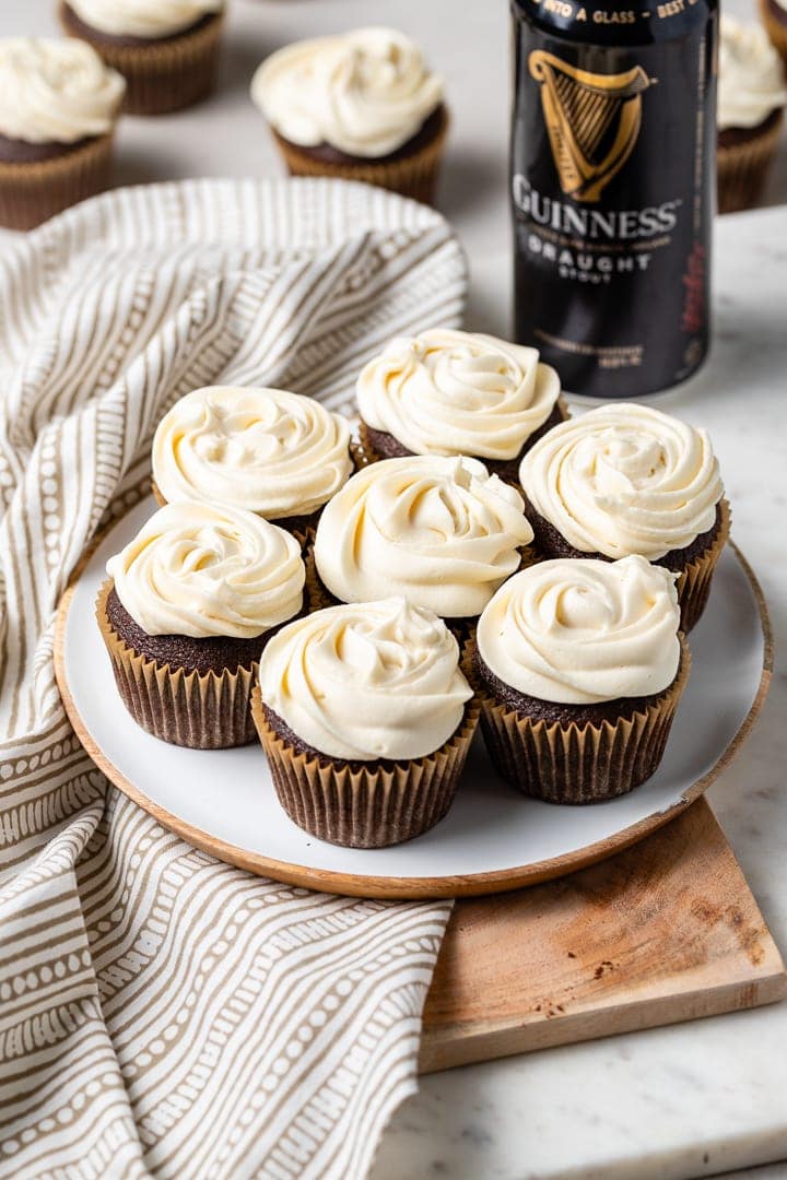 A small plate filled with the best chocolate Guinness cupcakes with Irish cream frosting, with a bottle of Guinness in the background.
