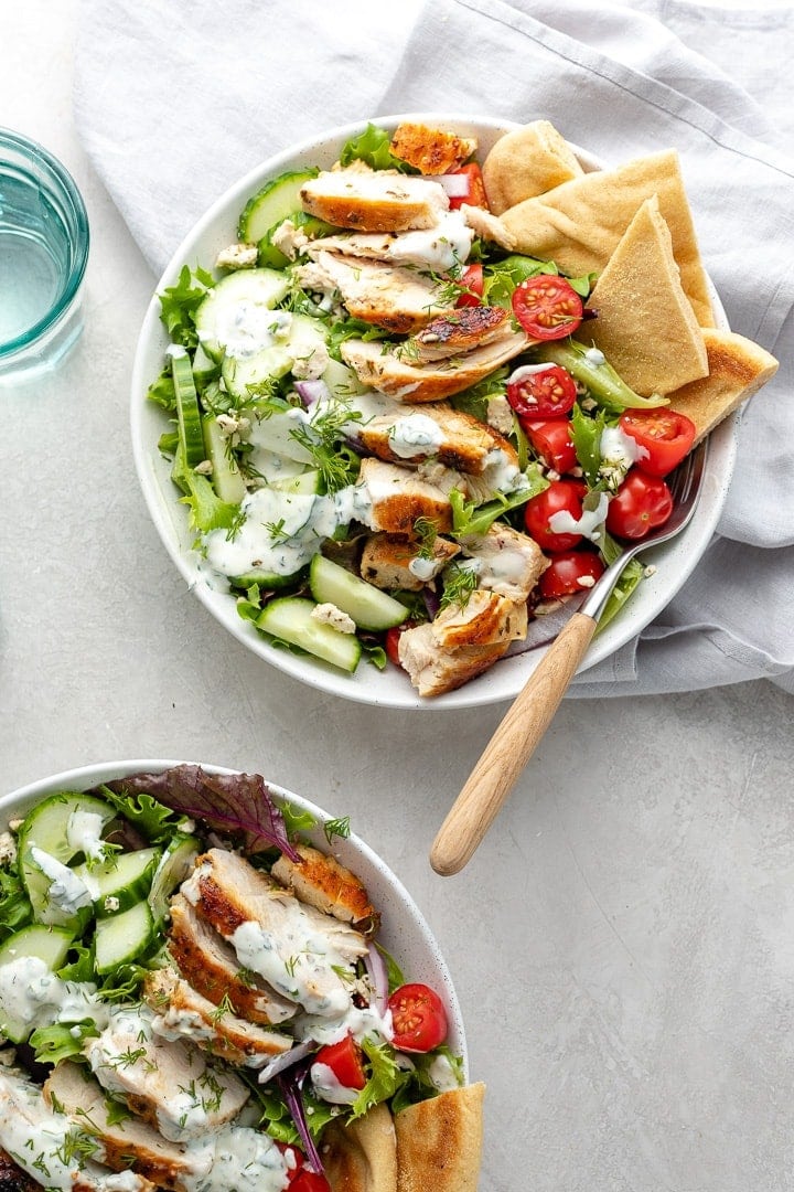 Prepared chicken gyro salad in a bowl with pita wedges and a fork.