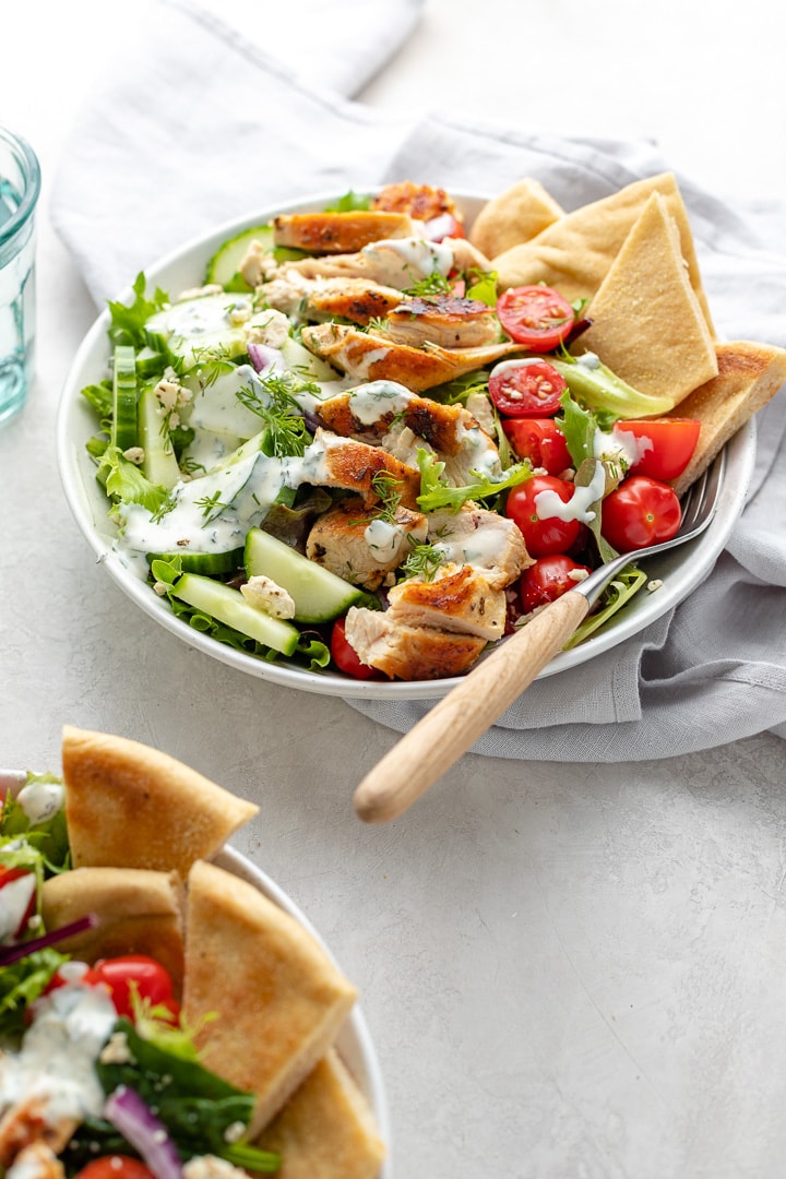 Prepared chicken gyro salad in a bowl with pita wedges and a fork.