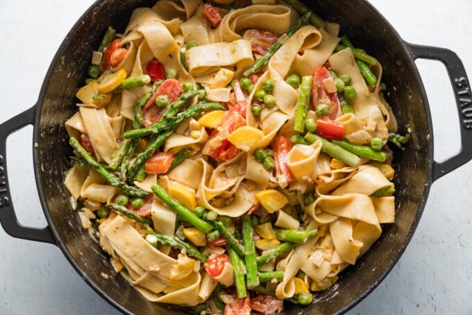 Creamy pasta primavera with pappardelle in a large cast iron skillet.