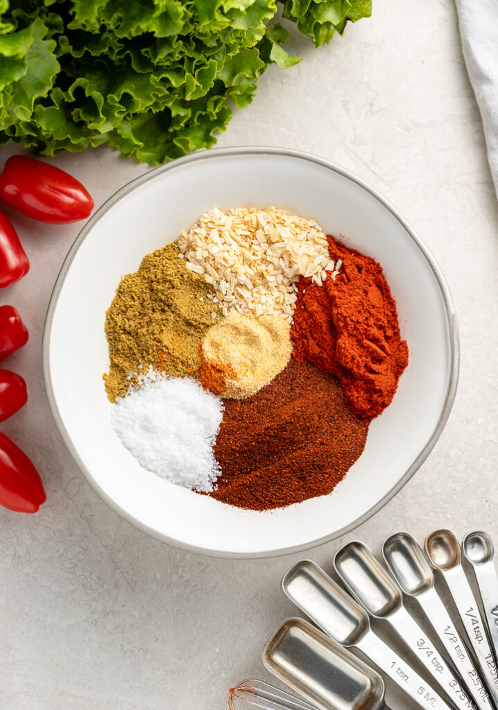 All the spices in homemade taco seasoning arranged in neat piles in a bowl.