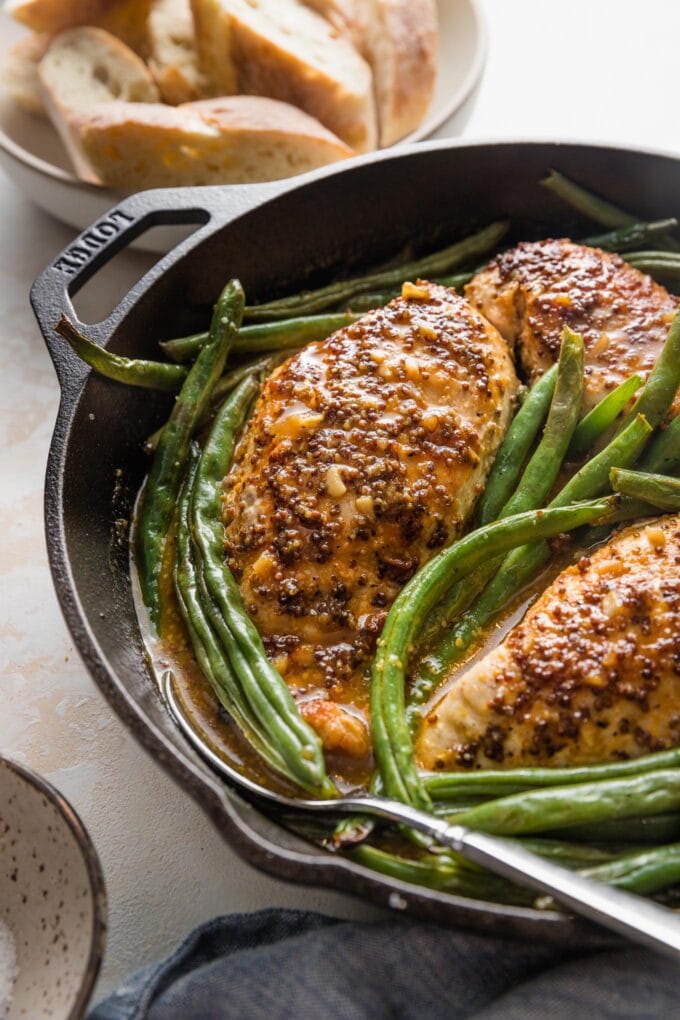 A honey mustard chicken skillet with a golden brown crust, rich pan sauce, and green beans, just out of the oven and ready to serve.