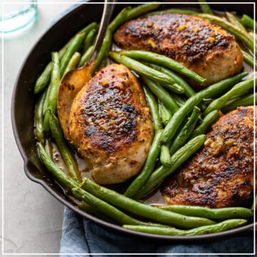 Close-up of honey mustard chicken cooked in a skillet with green beans.