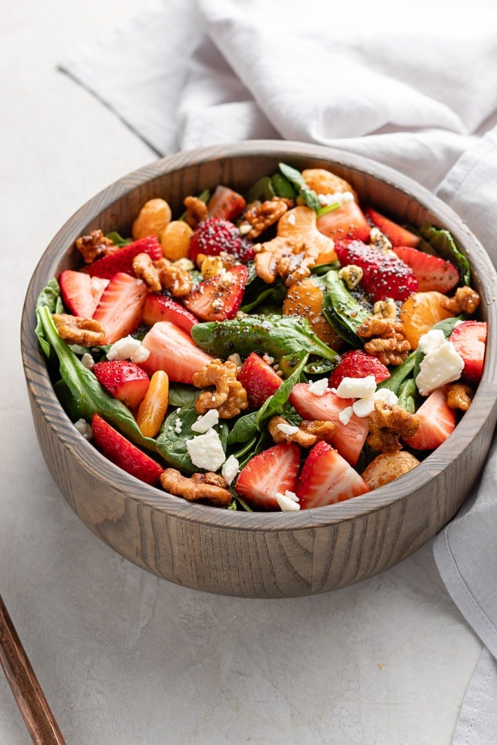 Close up of strawberry spinach salad in a bowl, ready to toss and serve.