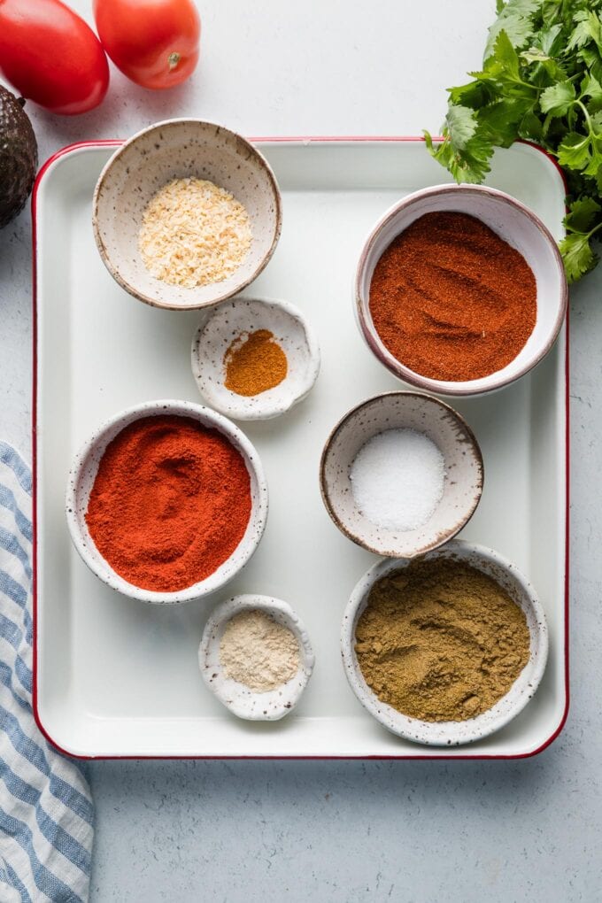Spices for a homemade taco seasoning blend measured out into cute, small prep bowls.