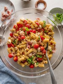 Bowl full of Caprese pasta salad with fresh mozzarella, tomatoes, fresh basil, prosciutto, pine nuts, and a homemade balsamic dressing.