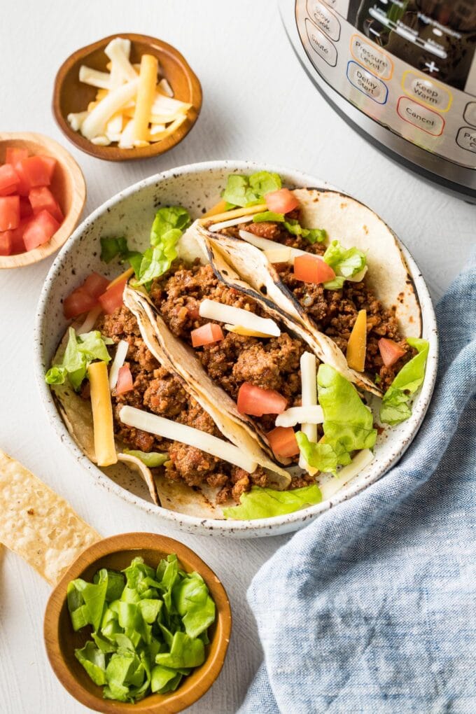 Plate with ground beef tacos and Instant Pot in the background.