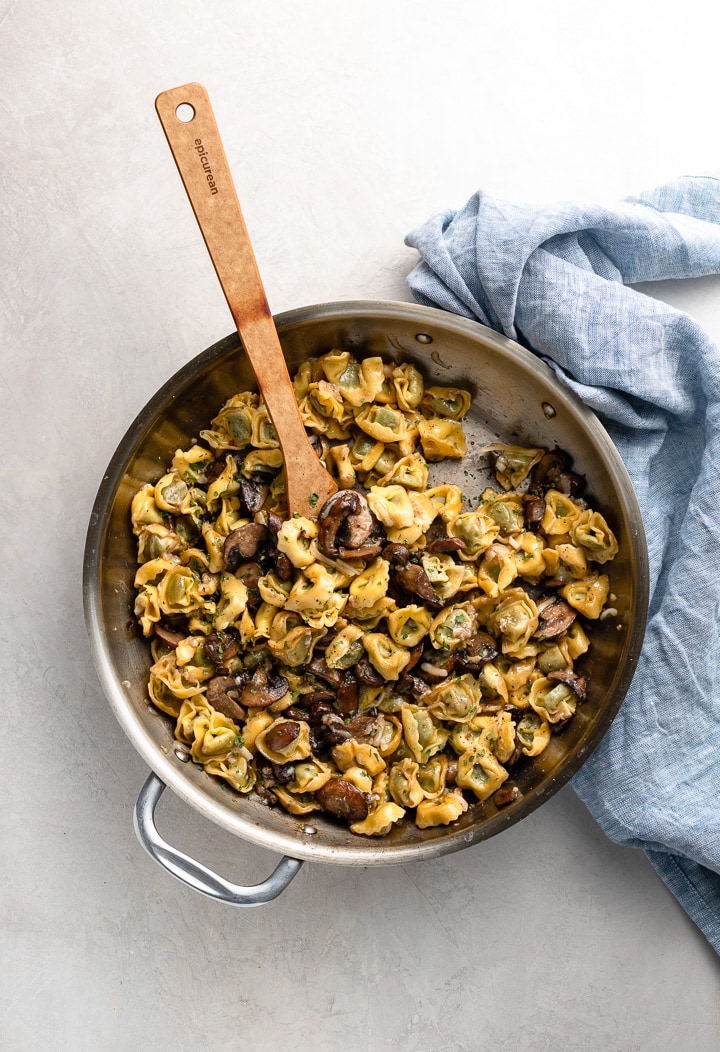 Skillet filled with cooked tortellini with mushrooms and Parmesan.