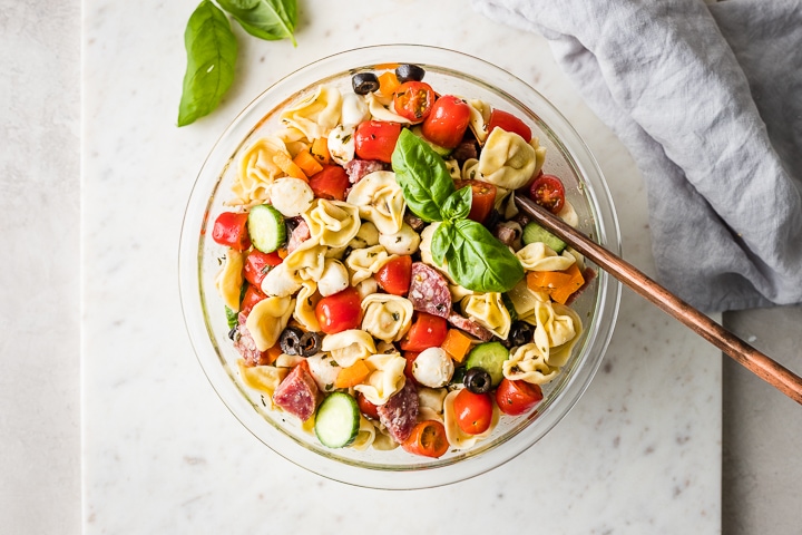 Overhead image of a large bowl and serving spoon ready to dish up some Italian pasta salad.