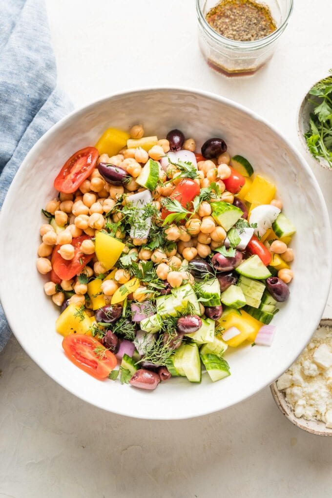 Bowl filled with rinsed chickpeas and fresh salad vegetables.