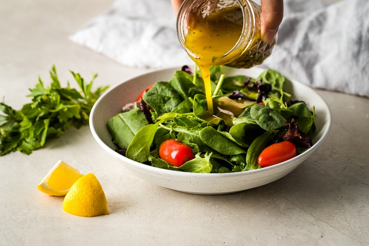 Pouring dressing over a simple salad.