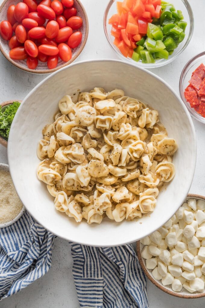 Bowl of cooked and cooled tortellini, tossed with Italian salad dressing.