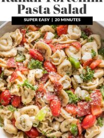 Close up of a bowl full of tortellini pasta salad loaded with peppers, pepperoni, tomatoes, mozzarella, and Italian dressing.