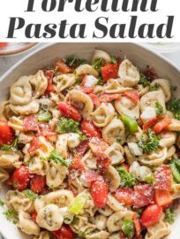 Close up of a bowl full of tortellini pasta salad loaded with peppers, pepperoni, tomatoes, mozzarella, and Italian dressing.