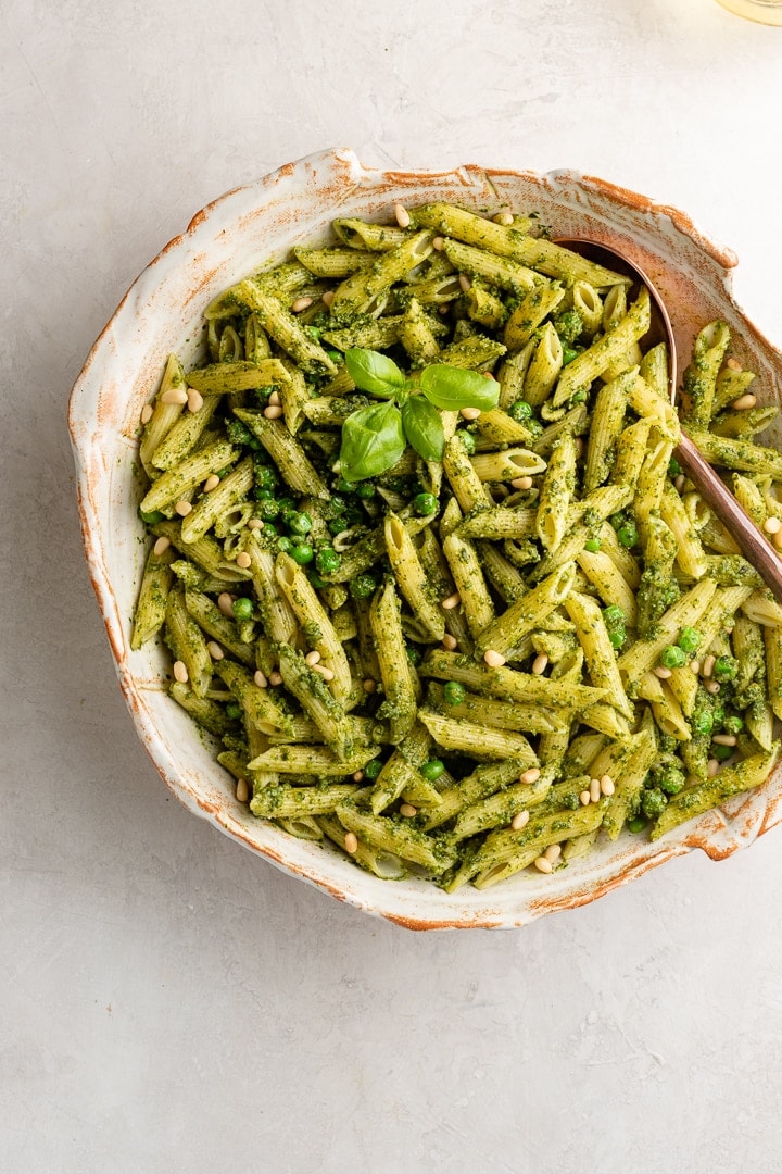 Large serving bowl filled with fresh pesto pasta with peas.