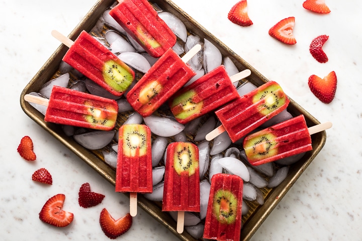 A tray filled with strawberry kiwi popsicles.