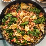 Cast iron pan full of a Tuscan white bean skillet dish, ready to serve.