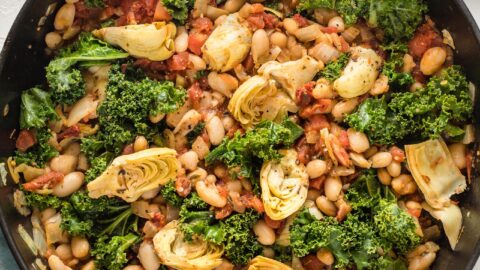 Cast iron pan full of a Tuscan white bean skillet dish, ready to serve.
