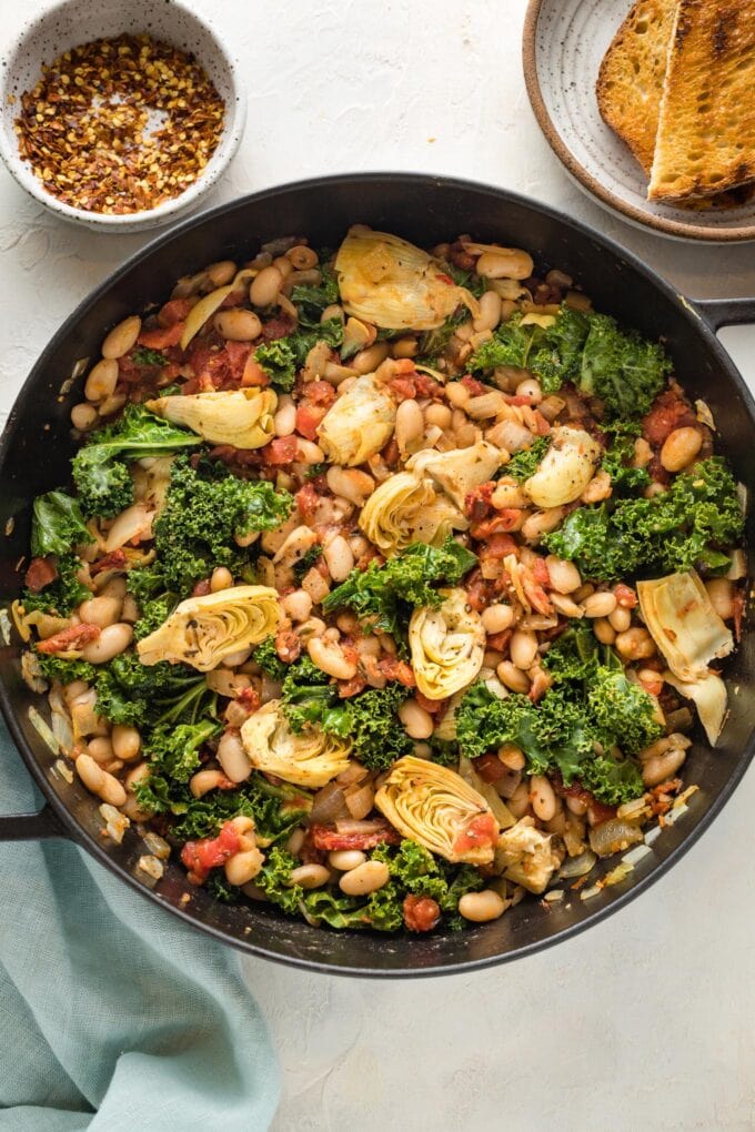 Cast iron pan full of a Tuscan white bean skillet dish, ready to serve.