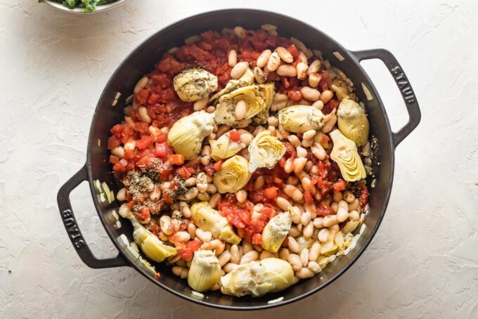 Beans, artichokes, and diced tomatoes added to skillet.