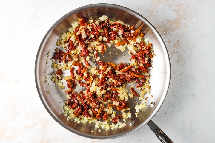 Photo of skillet with sauteed onions, garlic, and sun dried tomatoes.