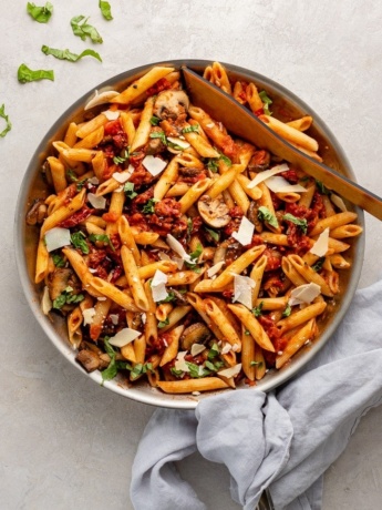 Skillet filled with penne alla vodka with mushrooms and sun-dried tomatoes.