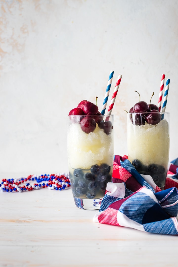 Two glasses filled with layered red, white, and blue frozen lemonade.