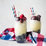 Two glasses filled with layered red, white, and blue frozen lemonade.