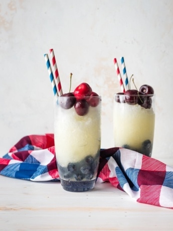Two glasses filled with layered red, white, and blue frozen lemonade.