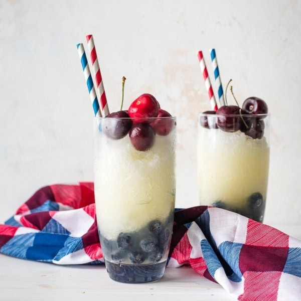 Two glasses filled with layered red, white, and blue frozen lemonade.