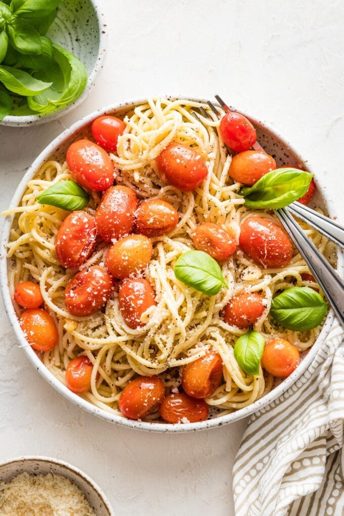 Close-up overhead image of roasted tomato pasta in a small bowl ready to eat with a fork.