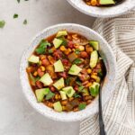 Close up of a bowl of summer vegetable chili, served with avocado.