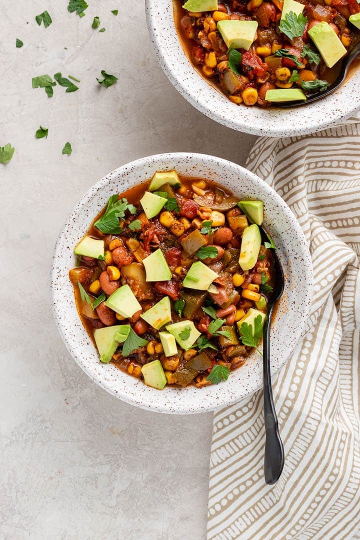 Close up of a bowl of summer vegetable chili, served with avocado.