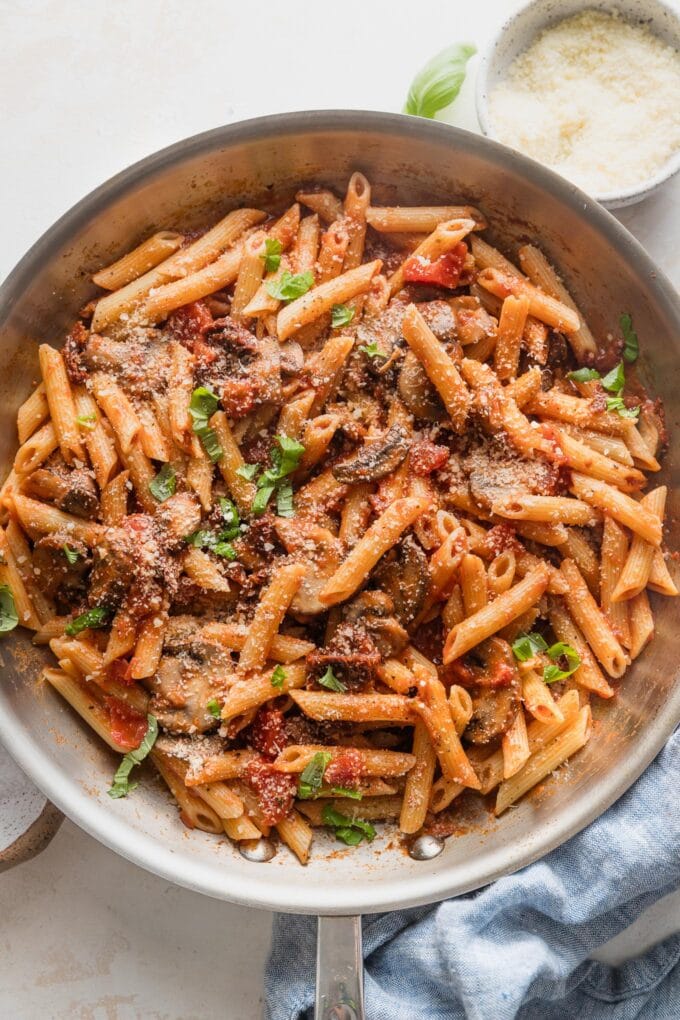Vodka penne skillet with mushrooms and fresh basil and Parmesan as a garnish.
