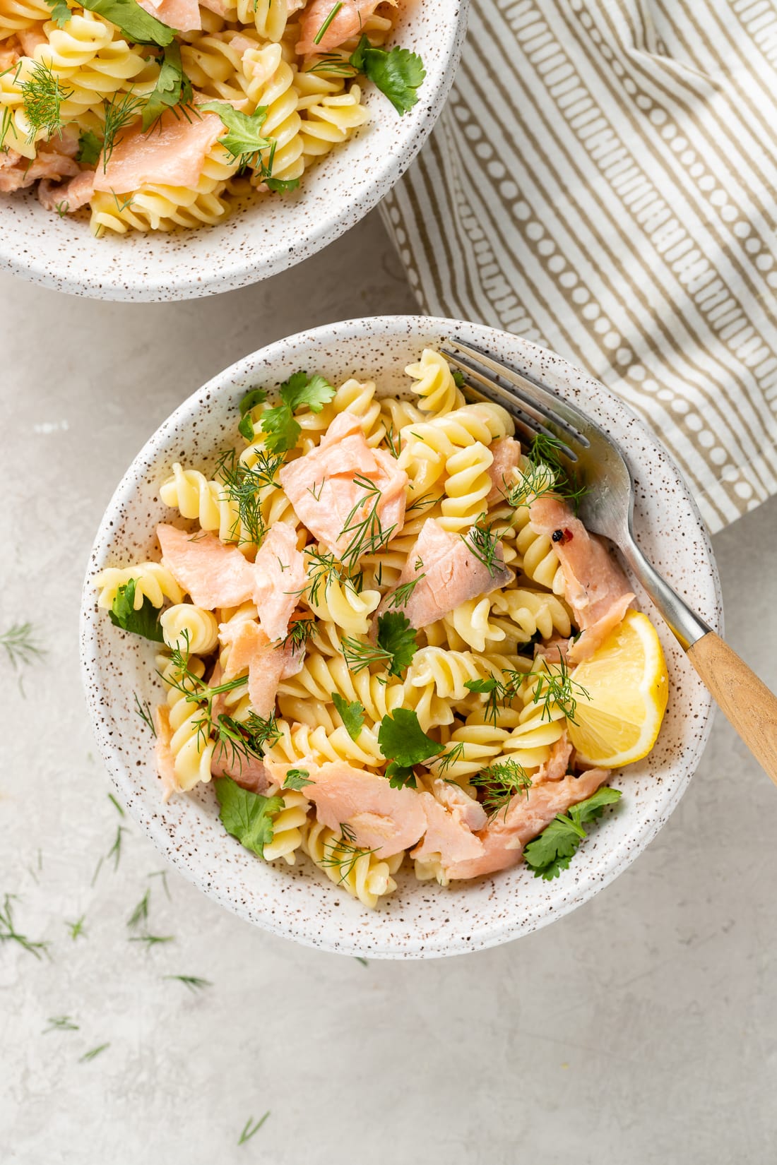 White bowl filled with a serving of Creamy Smoked Salmon Pasta with a lemon wedge.